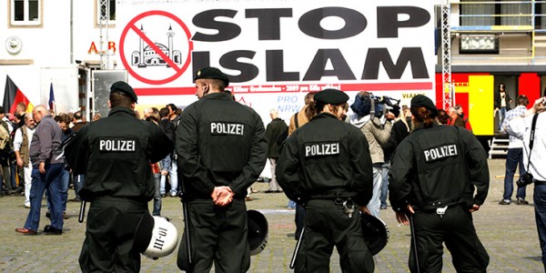 Police officers line up in front of a banner reading 'stop islam' during a demonstration in Cologne